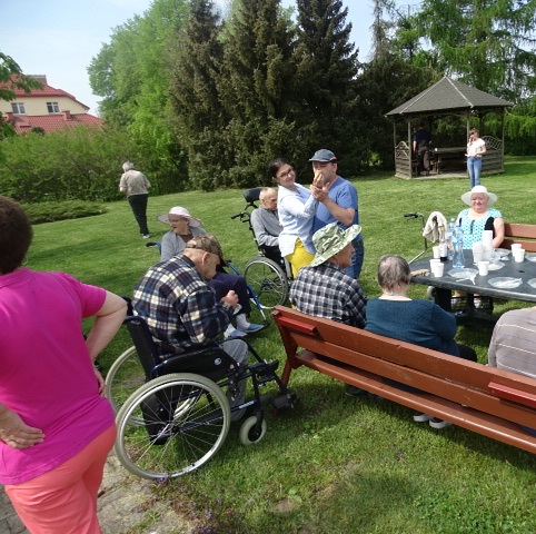grupa mieszkańców i opiekunów przy wspólnej zabawie przy ognisku w ogrodzie
